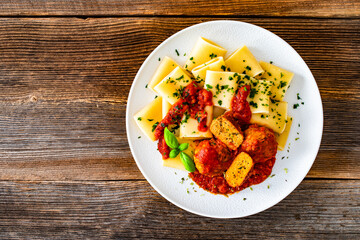Pasta with meatballs in bolognese sauce on wooden table	