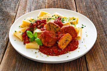 Pasta with meatballs in bolognese sauce on wooden table	
