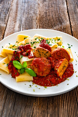 Pasta with meatballs in bolognese sauce on wooden table	