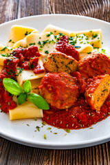 Pasta with meatballs in bolognese sauce on wooden table	