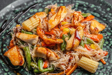 Stir fried rice noodles with chicken and vegetables served on a plate