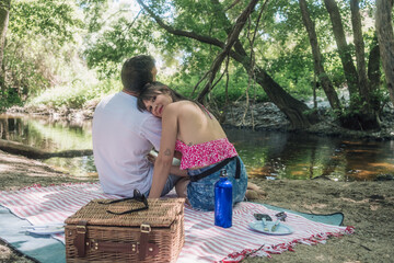 Couple enjoying romantic picnic by the river in summer