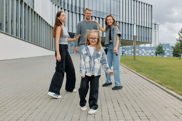 Fototapeta premium Portrait of a European family with two daughters walking hand in hand