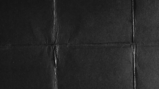 Black paper folded into grid with visible creases texture