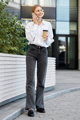 Fototapeta premium Young busy businesswoman using smartphone during lunch break on the street