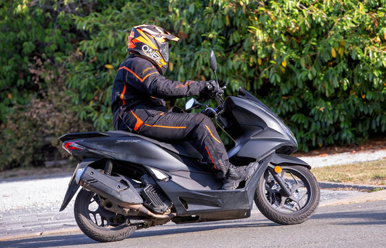 Whittlebury,Norhants,UK - Aug 23rd 2025:  Man riding a Honda PCX 125 scooter  driving on a British road