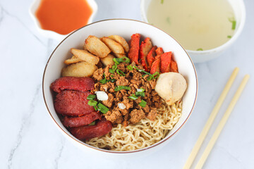 A hearty bowl of noodles with minced meat, red char siu, lap cheong, fish balls, fish cake, scallions, chili and clear soup. A delicious and popular Asian dish. Usually eaten with chopsticks.