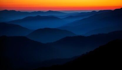 Naklejka premium Dramatic mountain landscape at sunset with vibrant orange sky and blue mist