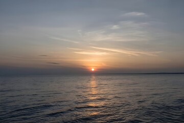 Serene ocean sunset with golden sun reflecting on rippling water