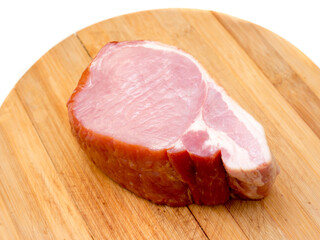 A piece of smoked ham on a wooden background.