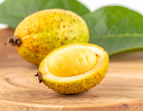 Yellow Bacuri fruit cut open showing its creamy pulp on wooden surface