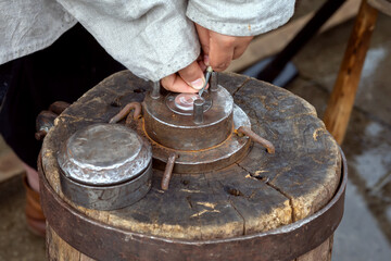 Blacksmith works hammer minting ancient coin during historical reconstruction amateur festiva. Tool for creating coins by embossing.