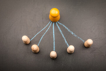 Leadership and delegation concept with wooden figures and chalk lines on blackboard