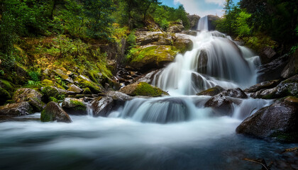 Obraz premium striking mountain waterfall rushes over rocks with silky motion captured in long exposure