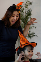 Halloween Celebration. Excited mother and daughter wearing festive hats, enjoying spooky fun.