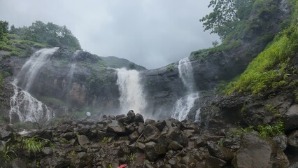Majestic Waterfall Cascading through Lush Green Hills and Rocks