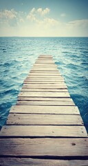 Obraz premium Wooden boardwalk extending into the ocean under a clear sky.