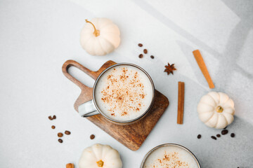 Warm spiced latte in mug with white pumpkins, cinnamon sticks, star anise and coffee beans.