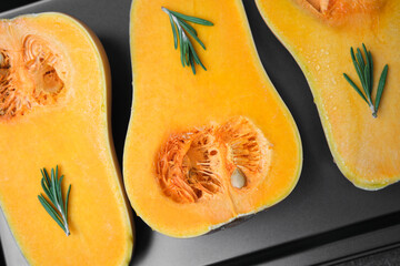 Halved butternut squash with rosemary sprigs on baking sheet, close up