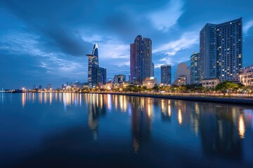 Fototapeta premium City skyline at dusk reflecting on a calm river, with illuminated buildings