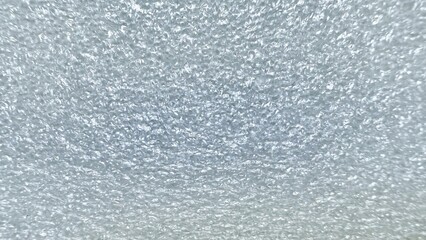 shimmering white styrofoam bubble wrap close up surface with reflective crinkle detail ideal for abstract background or packaging texture