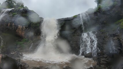 Majestic Waterfall Cascading through Lush Green Hills and Rocks