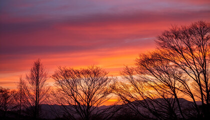 Fototapeta premium vibrant pink and orange sunset sky with scattered clouds over distant mountains