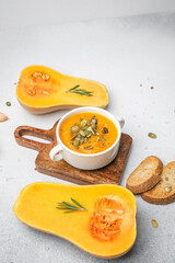 Butternut squash soup in white bowl with toasted bread and fresh rosemary