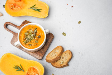 Creamy squash soup topped with seeds, served with toasted bread and pumpkin slices.