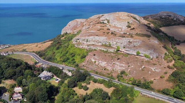 Aerial view of Little Orme hills of Llandudno, Wales with the sweeping coastline and clear blue sea on the background. 