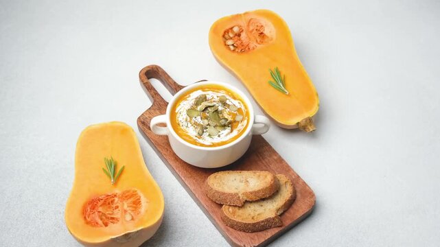Butternut squash soup with pumpkin seeds and bread served on wooden board