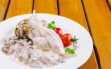 Creamy chicken dish served with fresh vegetables on a wooden table