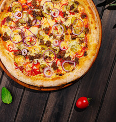 Delicious pizza topped with meat, olives, and fresh vegetables on wooden table