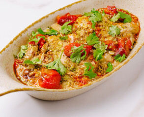 Delicious baked dish with peppers and herbs on a white table