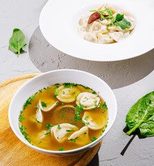 Delicious soup with dumplings served with fresh herbs in a bright setting