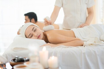 Fototapeta premium Couple enjoying herbal compress massage in spa. Promote wellness, stress relief, and modern self-care rituals.