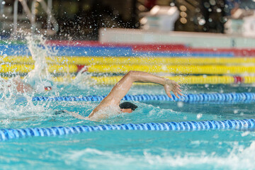 Athlete performing freestyle stroke during a swimming competition in indoor pool lanes