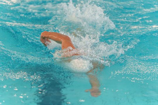 Athlete swimming freestyle in pool, practicing technique and improving endurance during training session