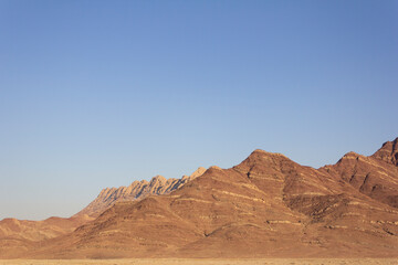 Arid desert mountains of Taft, Yazd, Iran under clear blue sky. Scenic natural landscape ideal for geology, travel, and nature backgrounds.