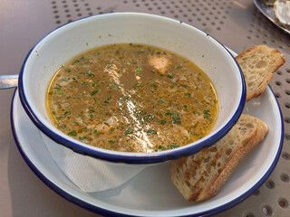  A rustic bowl of salmon fish soup with fresh parsley, served with two slices of bread, concept of a traditional meal and casual dining.