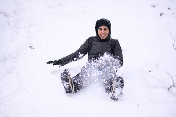 Happy tourist enjoying sledding down snowy hill in winter wonderland