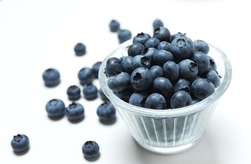 Glass bowl with fresh blueberries on wooden background