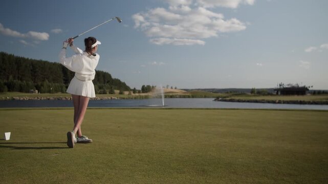 Woman golfer executes dynamic golf swing striking ball on course