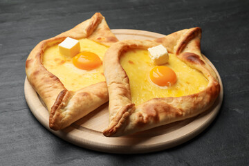 Tasty khachapuri with cheese and egg on black table, closeup