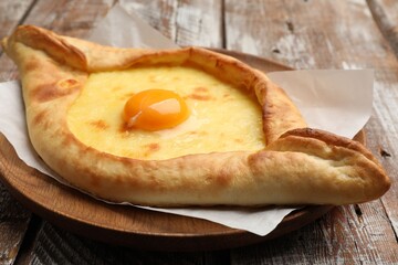 Tasty khachapuri with cheese and egg on wooden table, closeup