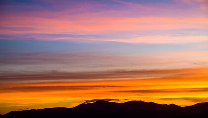 Vibrant sunset hues paint the sky above a silhouetted mountain range