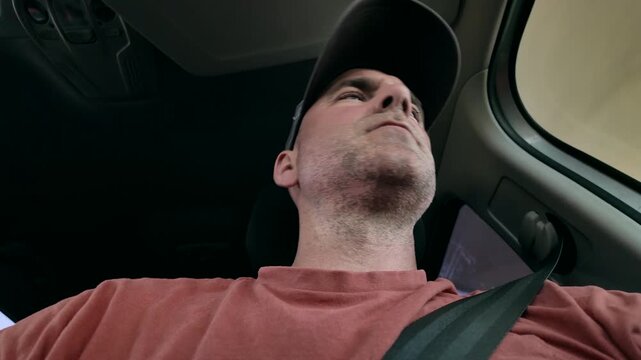 Low angle view, looking up at a casually dressed man driving a car.