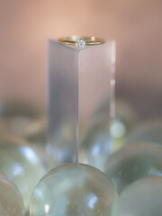 A diamond ring on a background of soft colors and shapes.