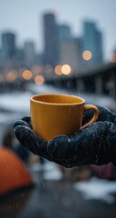A warm mug of drink held in a hand during winter weather.