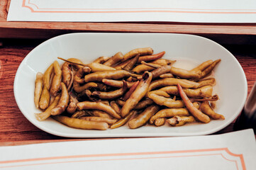 Spicy savory Pickled Jalapeno Chili Peppers in White Plate on Restaurant Table